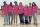 Six teenagers and a middle-aged woman stand with their arms around each other and are smiling for the camera. They are all wearing pink shirts.